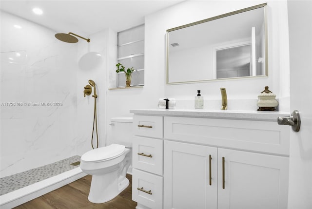 bathroom featuring vanity, toilet, wood-type flooring, and tiled shower