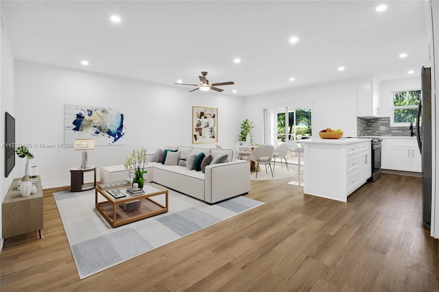 living room with ceiling fan and light hardwood / wood-style flooring