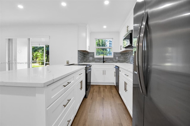 kitchen with tasteful backsplash, light stone counters, stainless steel appliances, hardwood / wood-style floors, and white cabinetry