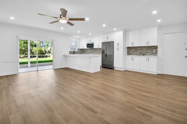 kitchen featuring kitchen peninsula, white cabinetry, stainless steel appliances, and light wood-type flooring