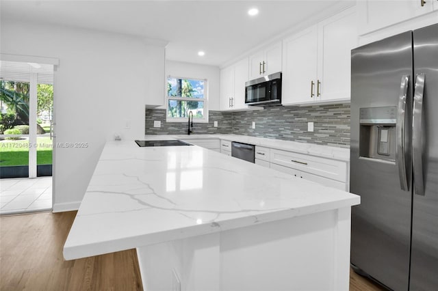 kitchen featuring stainless steel appliances, tasteful backsplash, light stone counters, light hardwood / wood-style flooring, and white cabinets