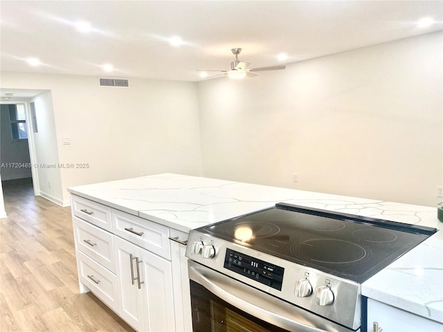 kitchen featuring light stone countertops, ceiling fan, electric range, light hardwood / wood-style flooring, and white cabinets