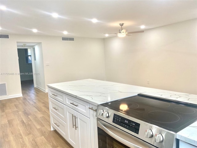 kitchen with light stone countertops, ceiling fan, light hardwood / wood-style floors, stainless steel electric stove, and white cabinets