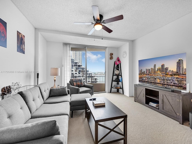 carpeted living room featuring ceiling fan and a textured ceiling