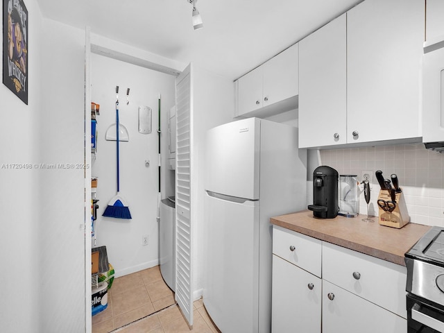 kitchen featuring light tile patterned floors, white appliances, white cabinets, light countertops, and backsplash