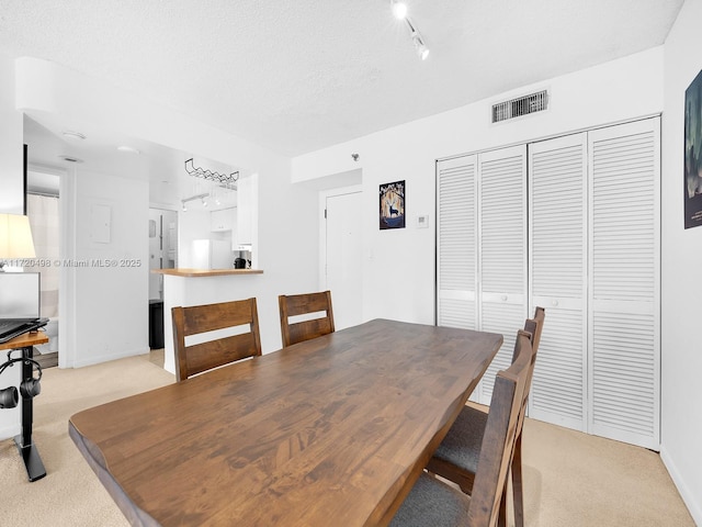 dining room featuring baseboards, visible vents, light carpet, and track lighting