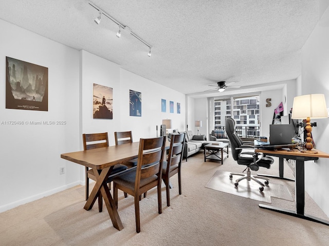 dining space featuring light carpet, baseboards, ceiling fan, a textured ceiling, and track lighting