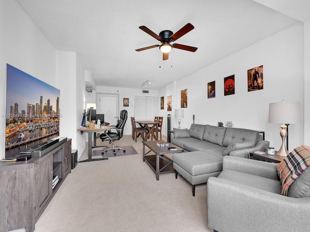 living area with a textured ceiling, a ceiling fan, and light colored carpet