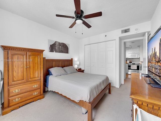 bedroom with light colored carpet, a closet, visible vents, and a textured ceiling