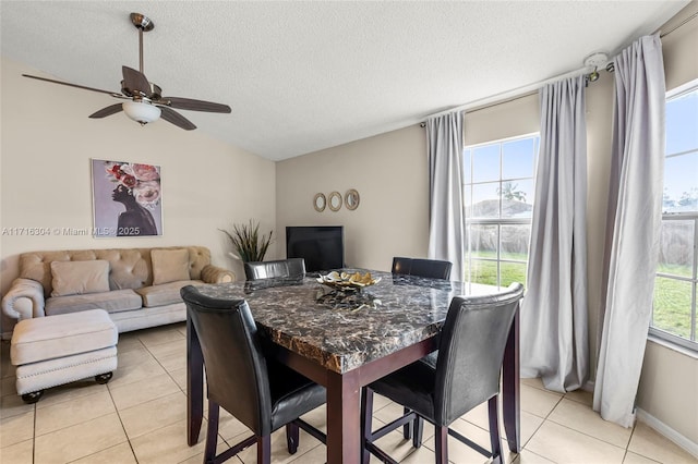 tiled dining area featuring vaulted ceiling, ceiling fan, and a textured ceiling