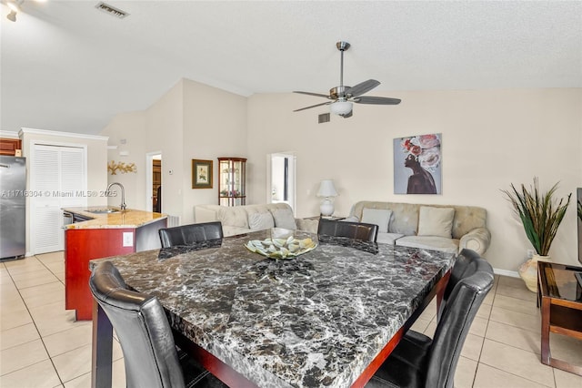 tiled dining area featuring a textured ceiling, ceiling fan, lofted ceiling, and sink