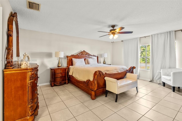 tiled bedroom with ceiling fan and a textured ceiling