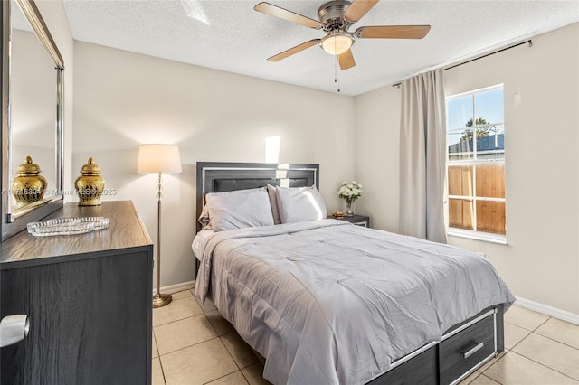 bedroom with ceiling fan, light tile patterned flooring, and a textured ceiling