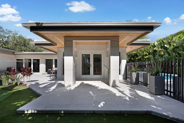 rear view of house featuring french doors, a patio area, fence, and stucco siding