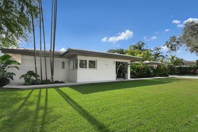 back of house featuring a yard and stucco siding