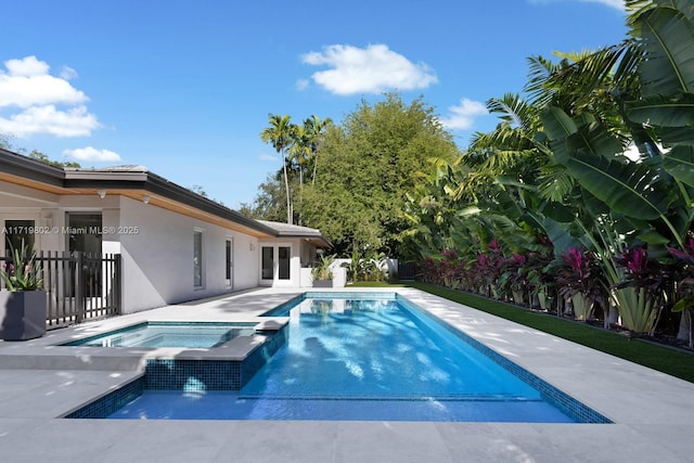 view of swimming pool with a pool with connected hot tub, fence, and a patio