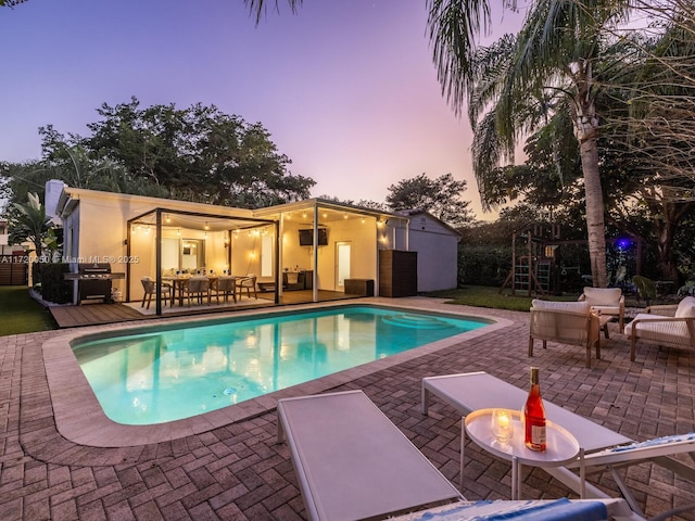 pool with outdoor dining space, a patio, a playground, and an outdoor hangout area