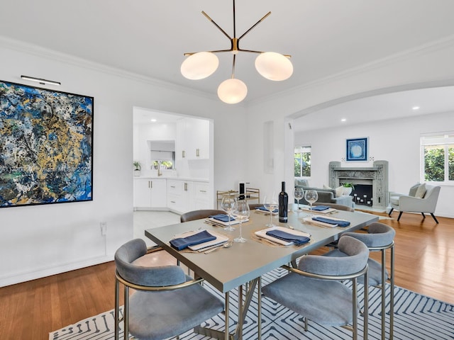 dining area featuring a high end fireplace, crown molding, recessed lighting, and light wood finished floors