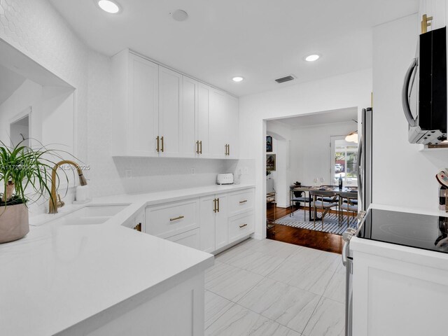 kitchen with range with electric cooktop, white cabinetry, and a sink