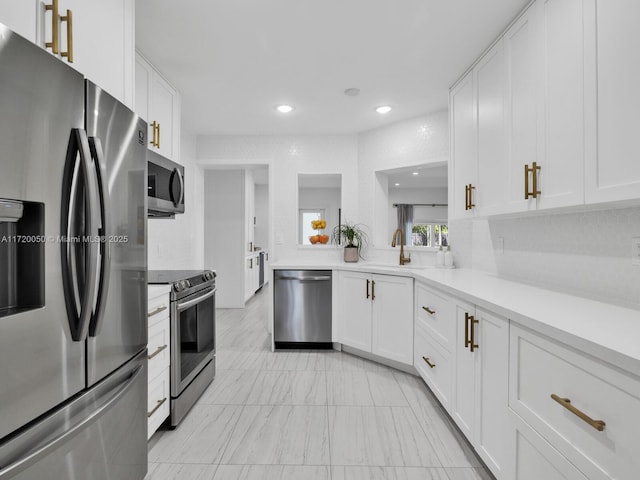 kitchen with light countertops, recessed lighting, appliances with stainless steel finishes, white cabinetry, and a sink