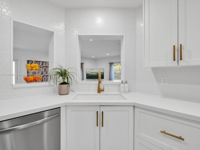 kitchen featuring tasteful backsplash, light countertops, stainless steel dishwasher, white cabinetry, and a sink