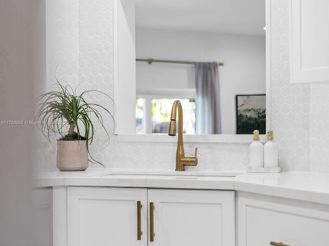 room details with white cabinetry, light countertops, tasteful backsplash, and a sink