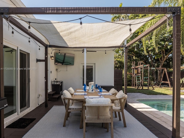 view of patio / terrace with an outdoor pool, outdoor dining area, and a playground