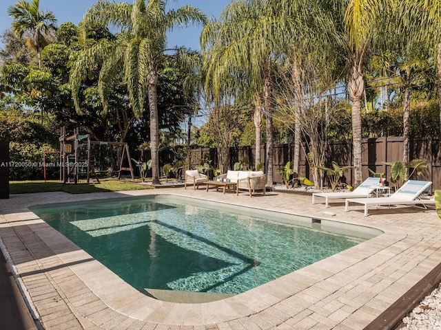 view of swimming pool with a fenced backyard, a playground, and a patio