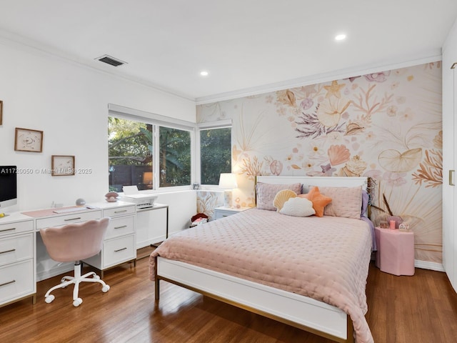 bedroom with visible vents, ornamental molding, wood finished floors, wallpapered walls, and baseboards