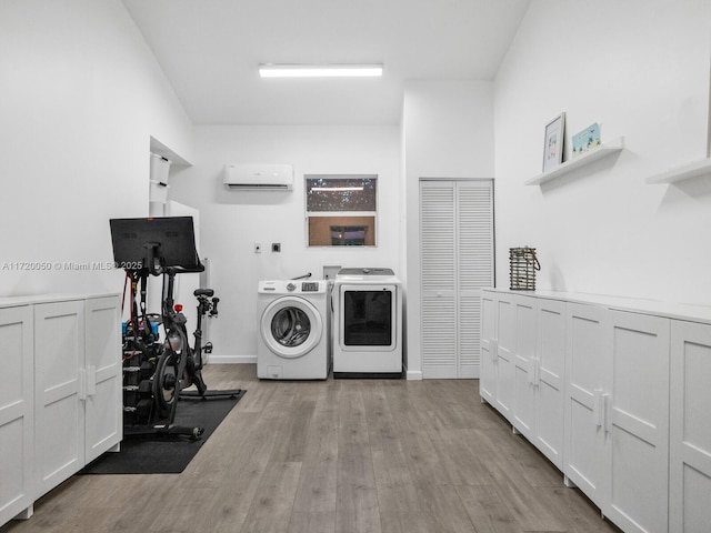 washroom with laundry area, light wood-type flooring, a wall mounted air conditioner, and washing machine and clothes dryer