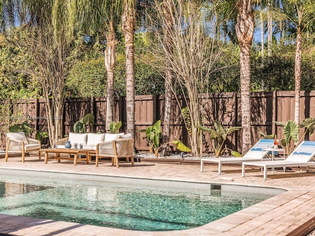 view of swimming pool with an outdoor living space, a patio, and a fenced backyard