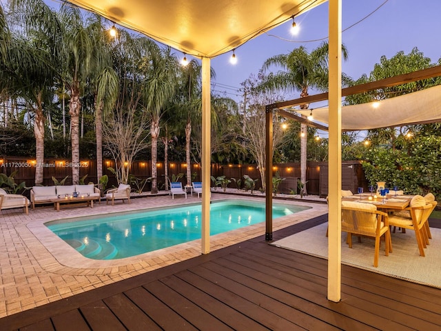 view of pool featuring a fenced in pool, a wooden deck, an outdoor living space, outdoor dining area, and a fenced backyard