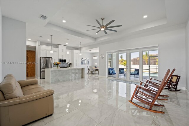 living room with ceiling fan and a tray ceiling