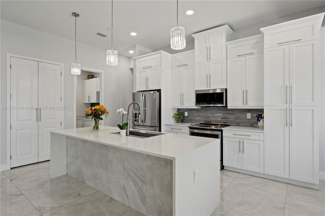 kitchen with pendant lighting, white cabinetry, stainless steel appliances, and an island with sink