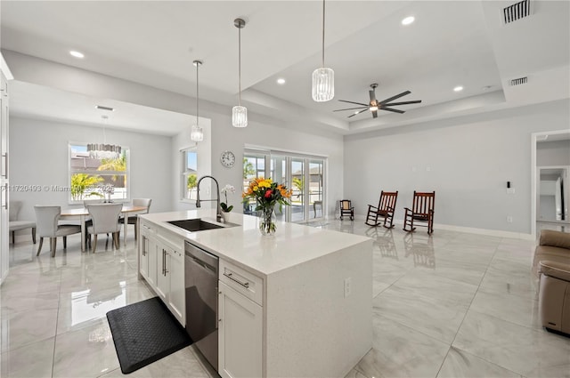 kitchen featuring stainless steel dishwasher, a raised ceiling, sink, white cabinetry, and an island with sink