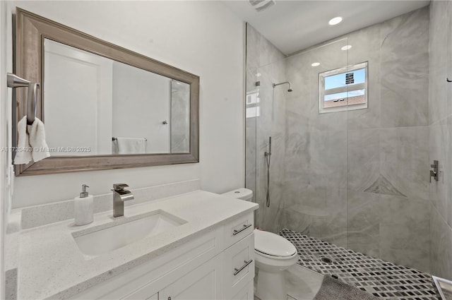 bathroom with tiled shower, vanity, and toilet