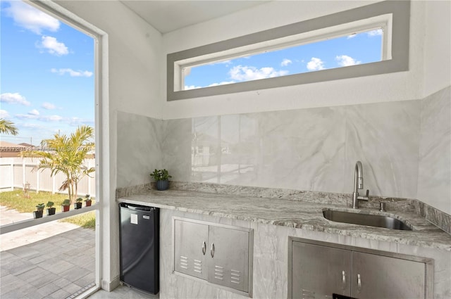 kitchen with light stone counters, sink, and fridge