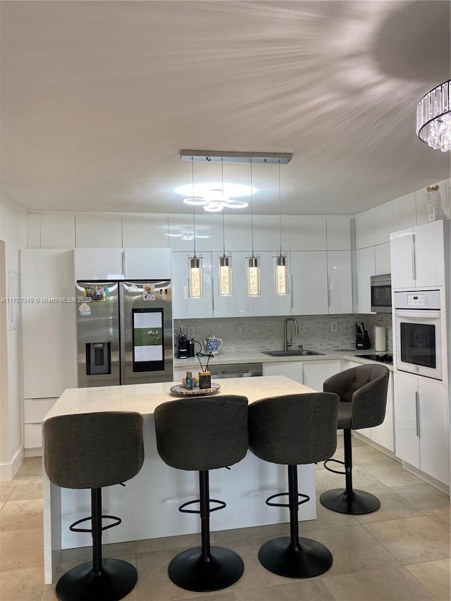 kitchen featuring pendant lighting, appliances with stainless steel finishes, a kitchen island, sink, and rail lighting