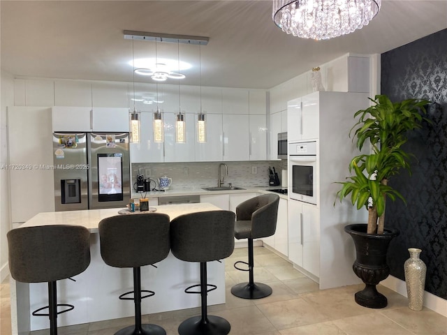 kitchen featuring a center island, white cabinetry, hanging light fixtures, sink, and stainless steel appliances