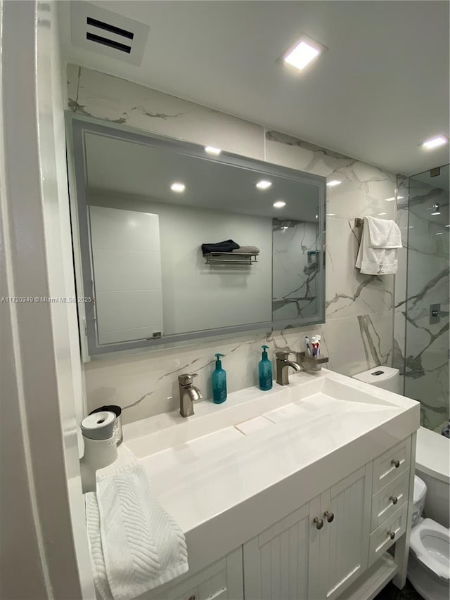 bathroom with toilet, tiled shower, and tasteful backsplash