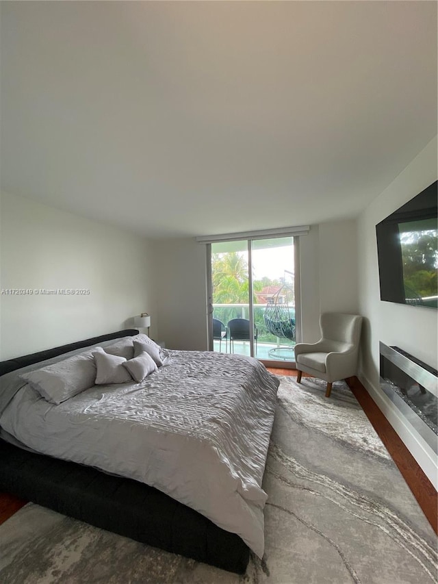 bedroom with hardwood / wood-style floors, floor to ceiling windows, and access to outside