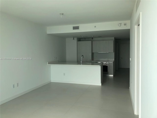 kitchen with kitchen peninsula, sink, light tile patterned flooring, and stove