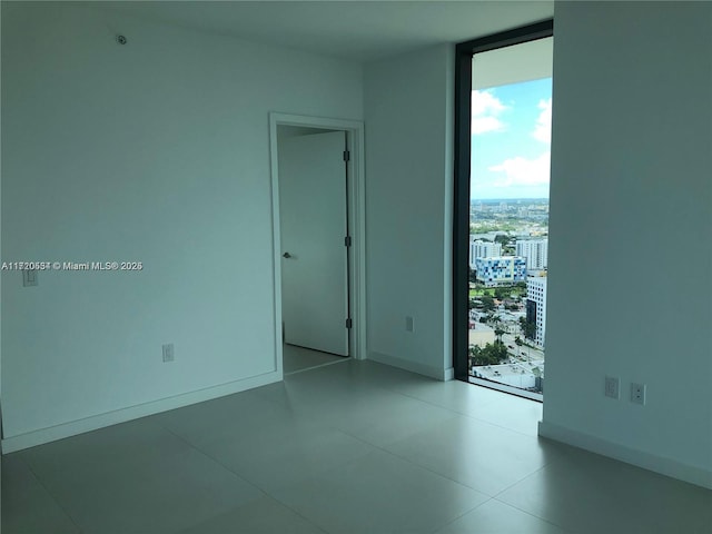 tiled spare room with a wall of windows