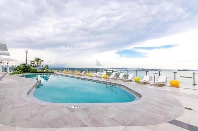 view of pool with a patio area and a water view