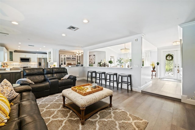 living room featuring an inviting chandelier, light hardwood / wood-style floors, and ornamental molding