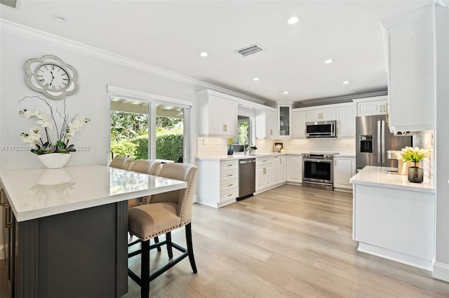 kitchen featuring kitchen peninsula, white cabinetry, a breakfast bar area, and appliances with stainless steel finishes