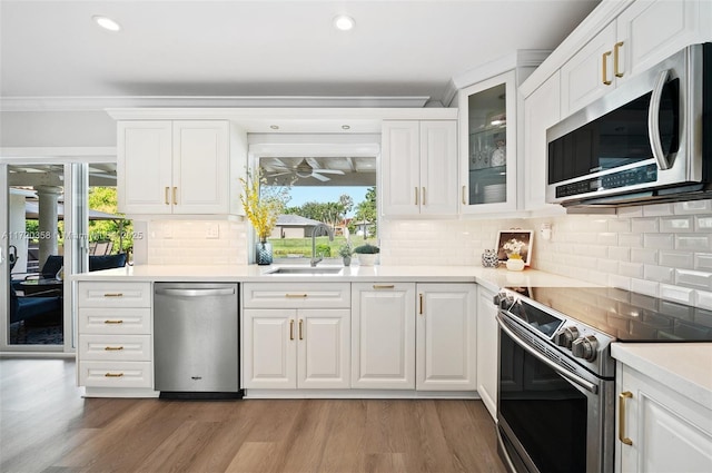 kitchen featuring backsplash, sink, light hardwood / wood-style flooring, appliances with stainless steel finishes, and white cabinetry