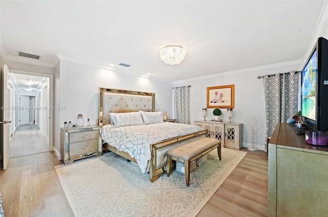 bedroom featuring light wood-type flooring, ornamental molding, and a chandelier