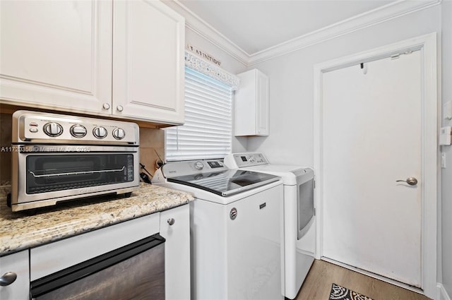 laundry room featuring cabinets, light hardwood / wood-style floors, crown molding, and washing machine and clothes dryer