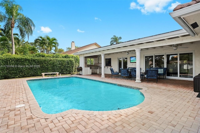 view of swimming pool featuring a patio, ceiling fan, and exterior kitchen